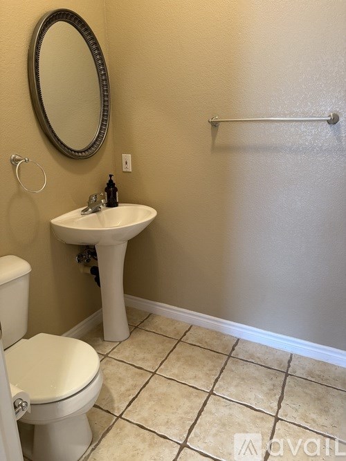 A bathroom with a toilet, sink, and mirror.