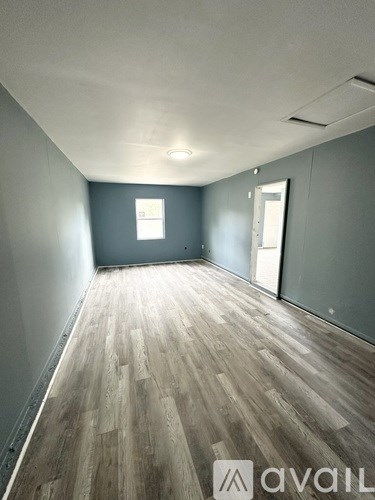 A room with wooden flooring and a window.