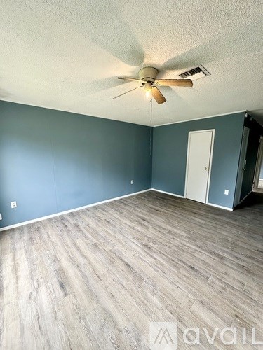 A room with a ceiling fan and wooden flooring.