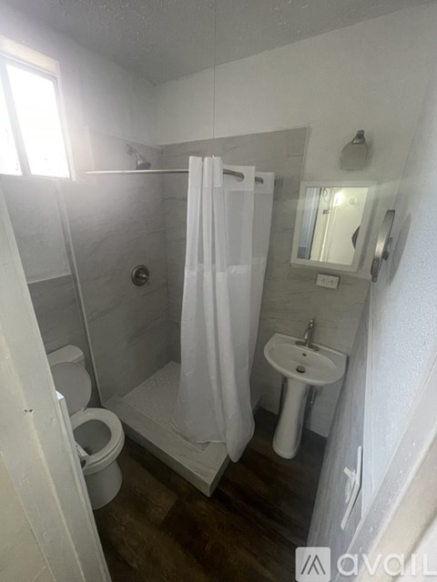 A small bathroom with a toilet, sink, and shower.