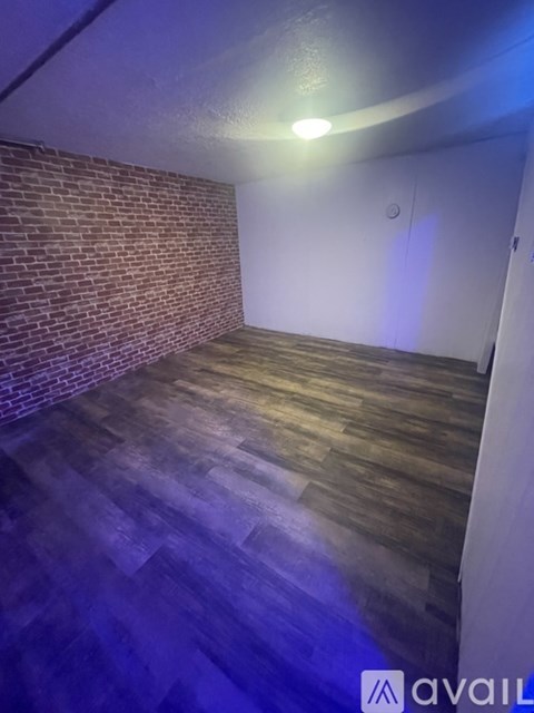 A room with wooden flooring and a brick wall.