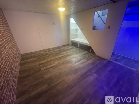 A room with wooden flooring and a brick wall.