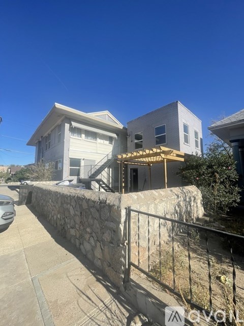 A house with a stone wall and a metal fence in front.