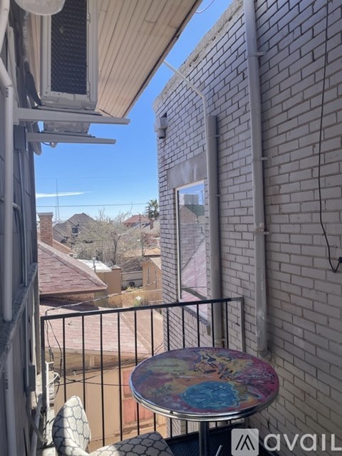A balcony with a table and chairs overlooking a mountainous landscape.