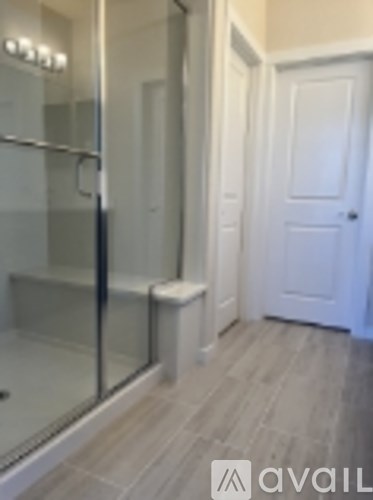 A bathroom with a glass shower door and a white door.