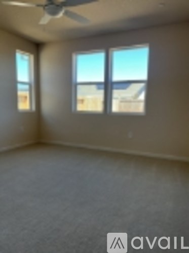 A room with a ceiling fan and three windows.