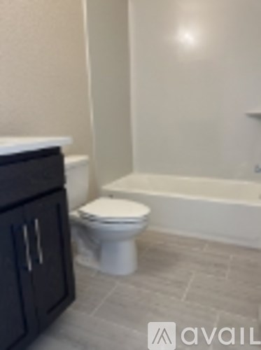 A white toilet in a bathroom with a black cabinet.