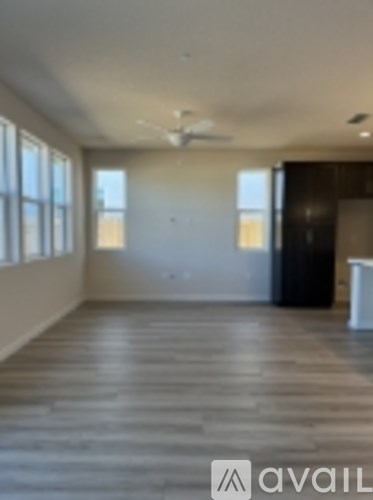 A spacious room with wooden flooring and a ceiling fan.