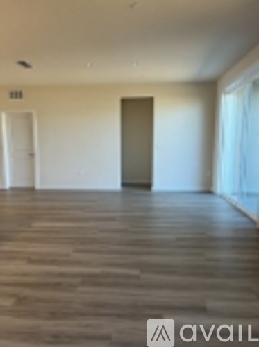 A room with wooden flooring and a door in the middle.