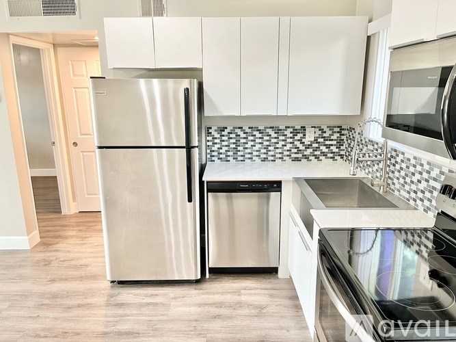A kitchen with a stainless steel refrigerator and a checkered backsplash.