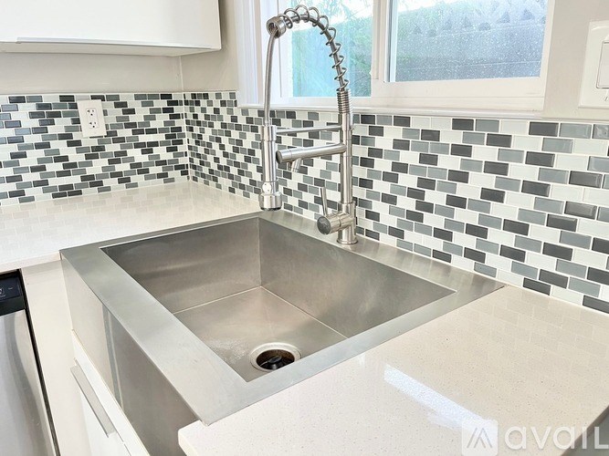 A kitchen sink with a chrome faucet and a window in the background.