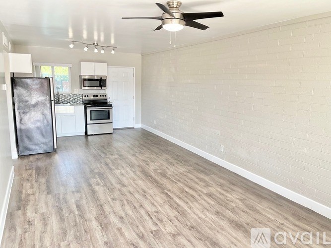 A spacious room with a ceiling fan and wooden flooring.