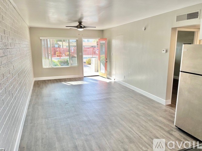 A spacious room with a ceiling fan and a refrigerator.