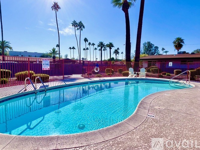 A pool surrounded by palm trees and a red fence.