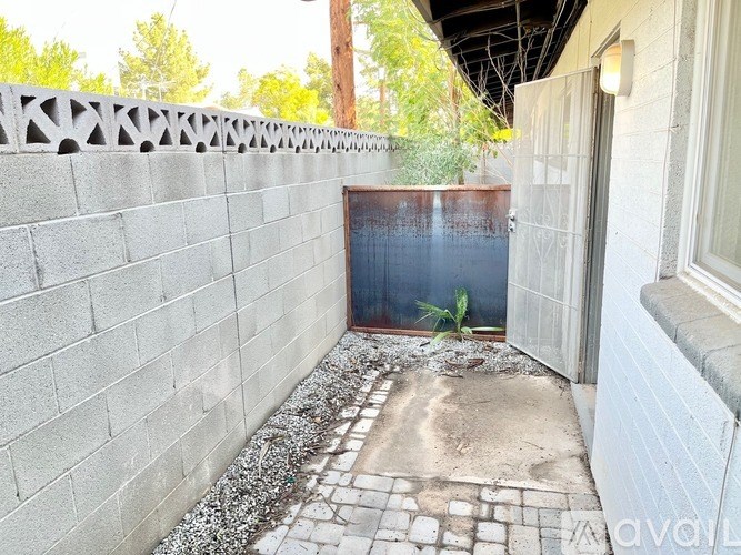 A small patio with a brick wall and a doorway leading to a backyard.