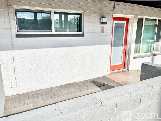 A red door is on the right side of a grey building.