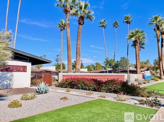 A house numbered 726 is surrounded by a garden with a row of palm trees.