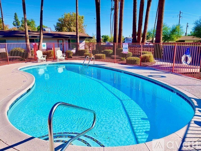 A pool surrounded by a fence and palm trees.