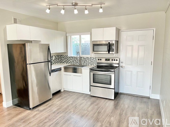 A kitchen with a stainless steel refrigerator, microwave, oven, and a white door.