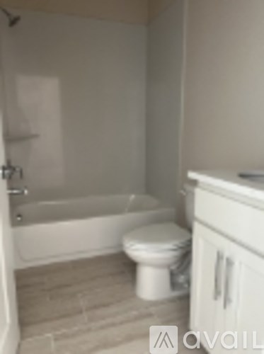 A white toilet sits in a bathroom next to a bathtub.