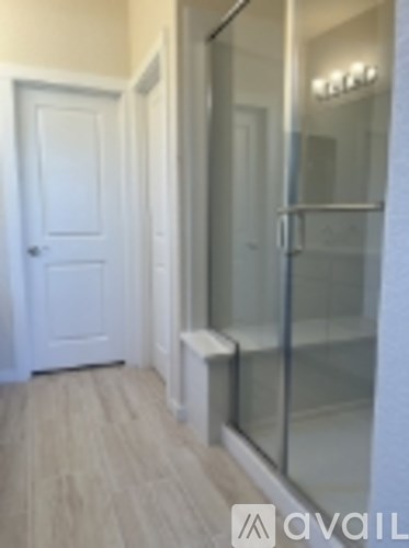 A white door is on the left of a glass shower stall.