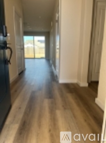 A long hallway with wood floors and white walls.