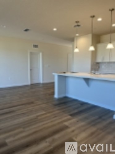 A room with wooden flooring and a counter in the background.