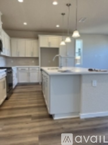 A kitchen with white cabinets and a wooden floor.