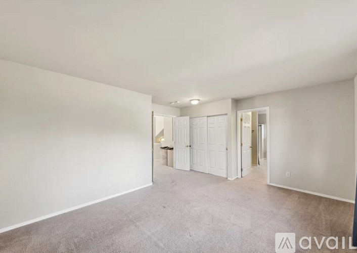 A spacious, empty room with white walls and carpeted floor.
