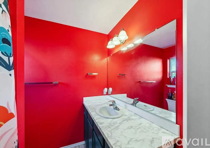 A bathroom with red walls and a marble counter.