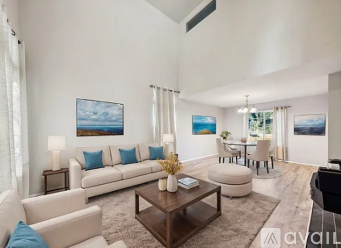 A living room with a white couch, a coffee table, and a painting on the wall.