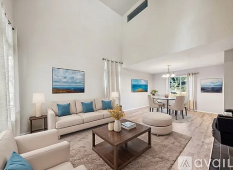 A living room with a white couch, a coffee table, and a painting on the wall.