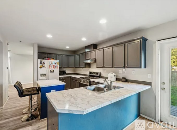 A kitchen with a blue island and a refrigerator with magnets on it.
