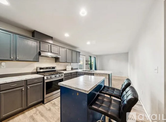 A kitchen with a black chair and a blue island.