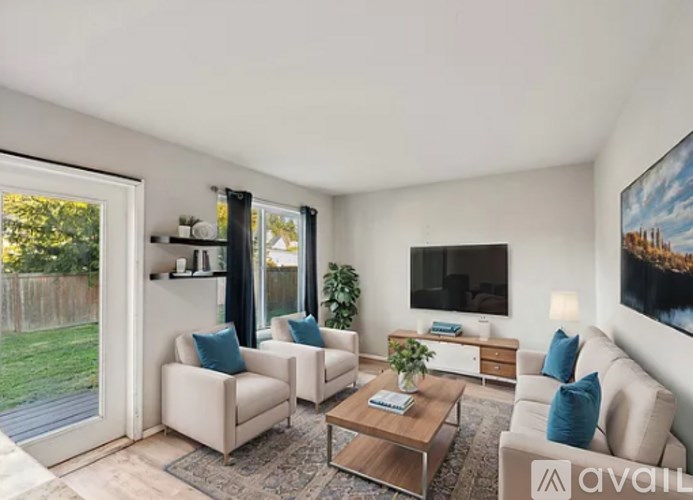 A living room with a sofa, two chairs, a coffee table, and a television.