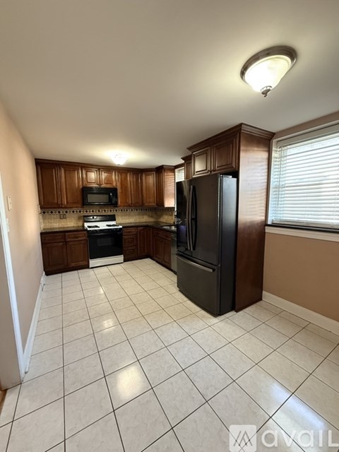 A kitchen with a black refrigerator and brown cabinets.