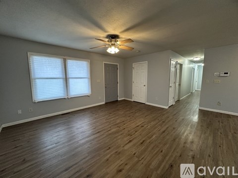 A spacious room with wooden flooring and a ceiling fan.