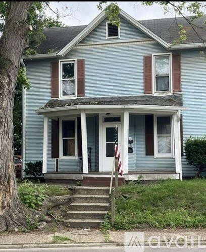 A blue house with a white door and a flag on the front porch.