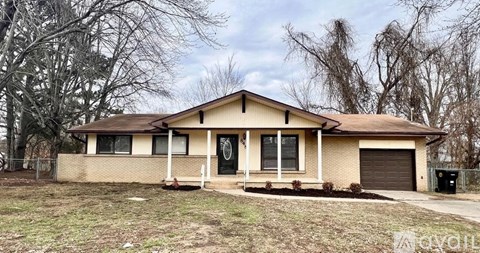A beige house with a black door and windows.