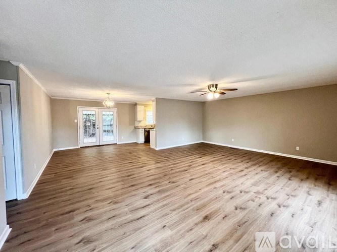 A spacious room with wooden flooring and a ceiling fan.