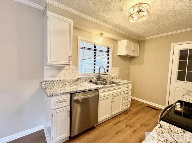 A kitchen with white cabinets and a granite countertop.