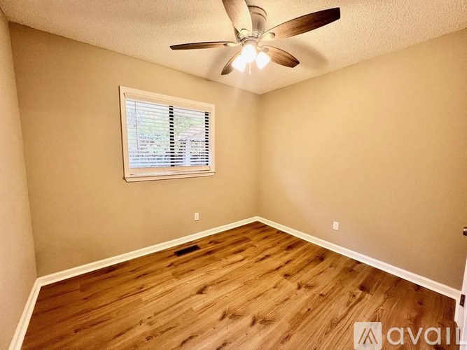 A room with a ceiling fan and a window with blinds.