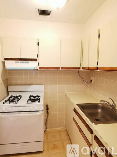 A white gas stove is in a kitchen with white cabinets and a white sink.
