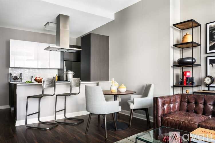 A modern kitchen with a brown leather couch and white chairs.