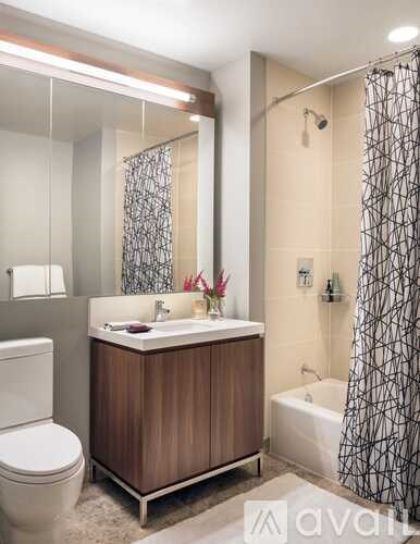 A modern bathroom with a wooden vanity and a shower with a black and white curtain.