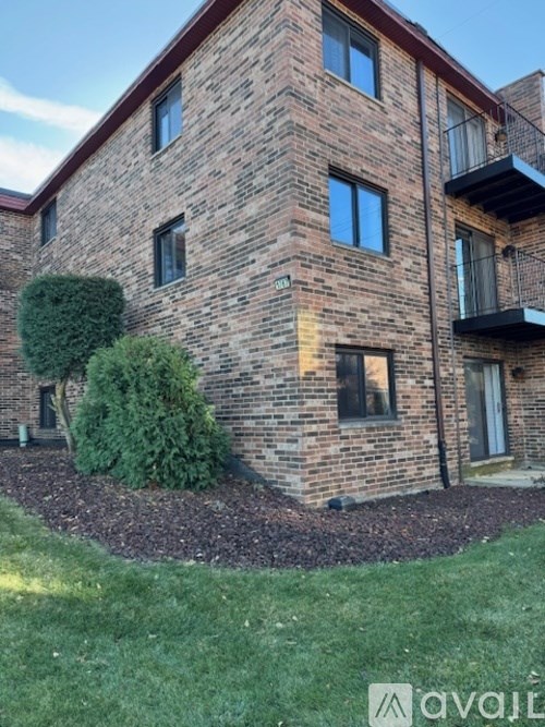 A brick building with a green bush in front.