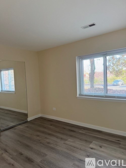 A room with a large mirror on the wall and a window with blinds.