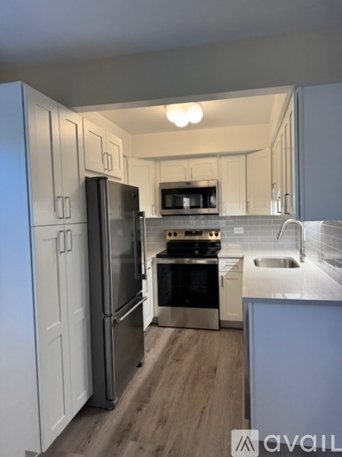 A kitchen with a refrigerator, oven, microwave, and sink.