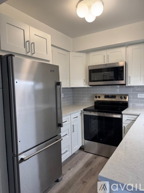 A kitchen with a stainless steel refrigerator and a microwave above the stove.