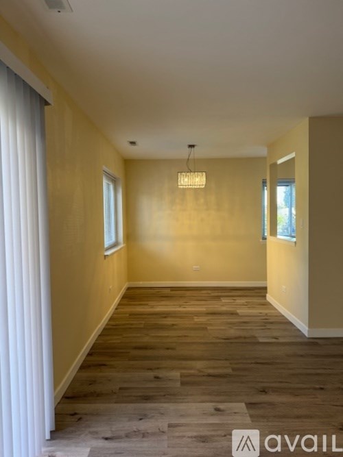 A room with wooden flooring and a chandelier hanging from the ceiling.
